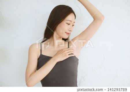 A young woman in a camisole smiles, showing her armpit. A young woman in a camisole smiles, showing her armpit. 141293789