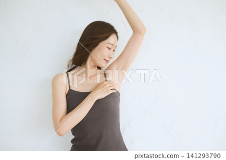 一位身穿吊帶背心的年輕女子微笑著,露出了腋窩。 一位身穿吊帶背心的年輕女子微笑著,露出了腋窩。 141293790