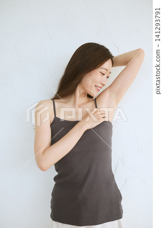 A young woman in a camisole smiles, showing her armpit. A young woman in a camisole smiles, showing her armpit. 141293791