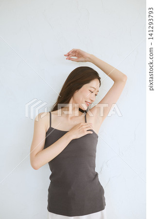 A young woman in a camisole smiles, showing her armpit. A young woman in a camisole smiles, showing her armpit. 141293793