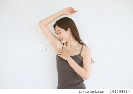 A young woman in a camisole smiles, showing her armpit. A young woman in a camisole smiles, showing her armpit. 141293814