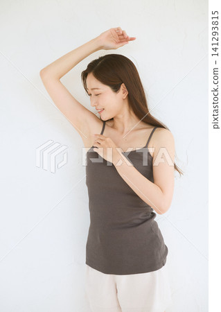 A young woman in a camisole smiles, showing her armpit. A young woman in a camisole smiles, showing her armpit. 141293815