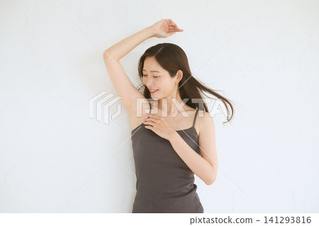 A young woman in a camisole smiles, showing her armpit. A young woman in a camisole smiles, showing her armpit. 141293816