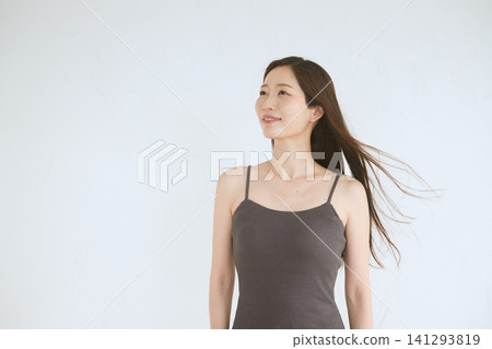 A young Japanese woman with a smile and flowing hair against a white background. A young Japanese woman with a smile and flowing hair against a white background. 141293819