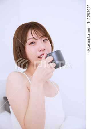 A young woman with short hair poses, holding a coffee cup. A young woman with short hair poses, holding a coffee cup. 141293913