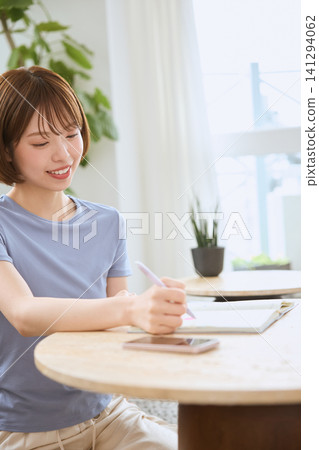 A smiling young woman using her smartphone in the living room. A smiling young woman using her smartphone in the living room. 141294062