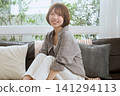 一位留著短髮的年輕女子坐在沙發上微笑。 一位留著短髮的年輕女子坐在沙發上微笑。 141294113