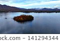 Aerial view of a secluded island of autumn leaves floating on the tranquil Akimoto Lake. Aerial view of a secluded island of autumn leaves floating on the tranquil Akimoto Lake. 141294344