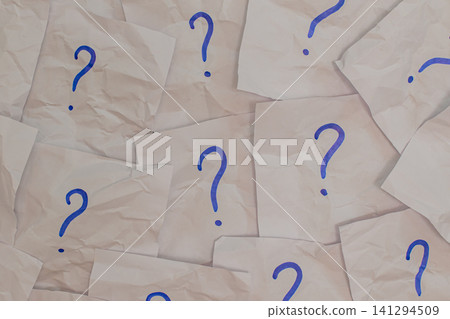 Horizontal top down view of many crumpled white paper notes with blue handwritten question marks scattered on a flat surface representing confusion and doubt Horizontal top down view of many crumpled white paper notes with blue handwritten question marks scattered on a flat surface representing confusion and doubt 141294509