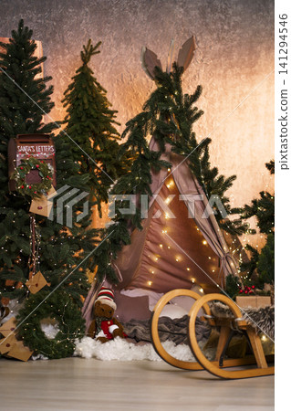 Cozy children's Christmas teepee with fairy lights, wooden sled and holiday decor Cozy children's Christmas teepee with fairy lights, wooden sled and holiday decor 141294546