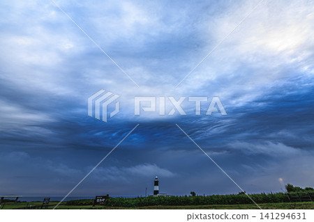 暴風雨雲層籠罩著諾托羅岬的天空,美麗的黑白相間的諾托羅燈塔孤零零地矗立在那裡。 暴風雨雲層籠罩著諾托羅岬的天空,美麗的黑白相間的諾托羅燈塔孤零零地矗立在那裡。 141294631