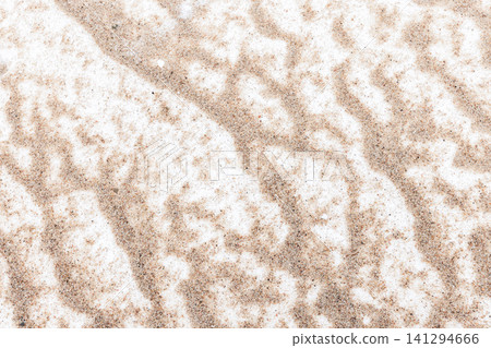 Snow dusted sand on a beach forming abstract winter patterns Snow dusted sand on a beach forming abstract winter patterns 141294666
