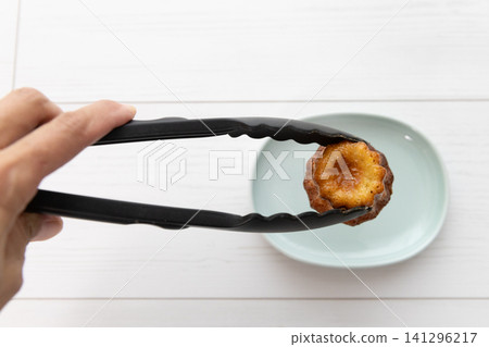 用黑色夾子將可露麗放在淺藍色盤子上。 用黑色夾子將可露麗放在淺藍色盤子上。 141296217