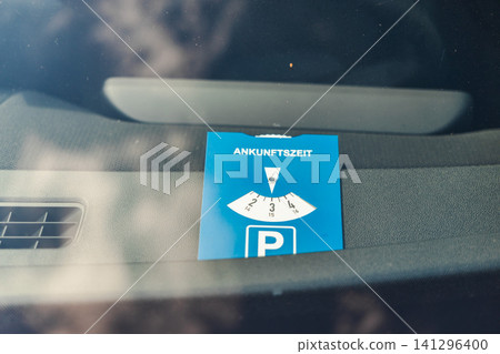 German parking disc with inscription "Ankunftszeit" translated as "arrival time" displayed inside vehicle for regulated public parking German parking disc with inscription "Ankunftszeit" translated as "arrival time" displayed inside vehicle for regulated public parking 141296400