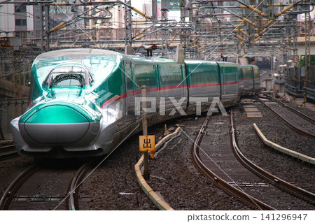 The streamlined front car of the Tohoku Shinkansen E5 series train running on the tracks. The streamlined front car of the Tohoku Shinkansen E5 series train running on the tracks. 141296947