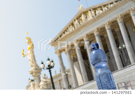 Plastic water bottle in front of the Austrian Parliament, symbolizing extreme summer temperature and rising heat impacts in Europe Plastic water bottle in front of the Austrian Parliament, symbolizing extreme summer temperature and rising heat impacts in Europe 141297081