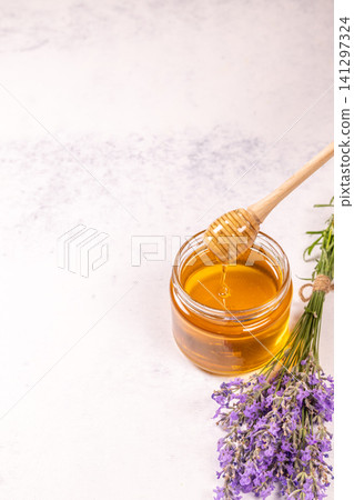 Honey jar with dipper and lavender flowers on white background Honey jar with dipper and lavender flowers on white background 141297324