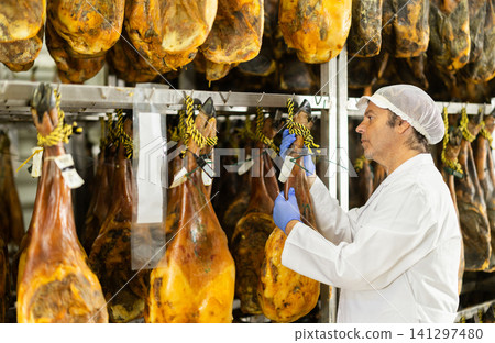 Man employee checks jamon. Quality control Man employee checks jamon. Quality control 141297480