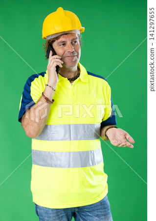 Man in special reflective clothing answers a call on a green background Man in special reflective clothing answers a call on a green background 141297655
