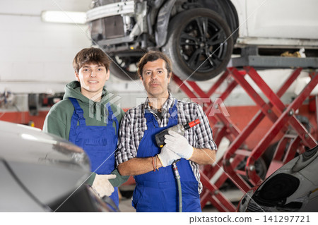 Guy and man mechanics posing in car repair shop Guy and man mechanics posing in car repair shop 141297721
