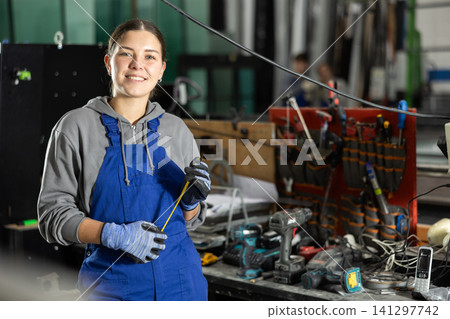Girl glazer employee in blue overall works in glass processing shop 141297742