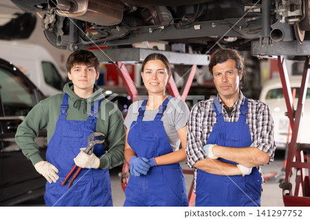 Professional team of auto repair shop posing next to hydraulic lift Professional team of auto repair shop posing next to hydraulic lift 141297752