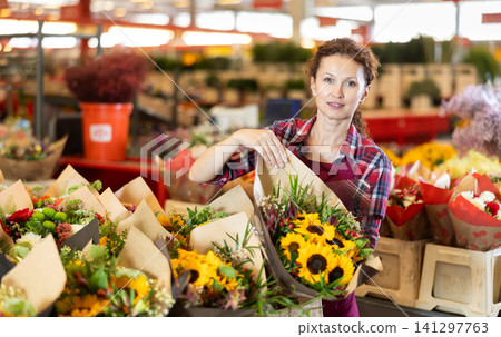 Adult female seller holding bouquet of flowers Adult female seller holding bouquet of flowers 141297763