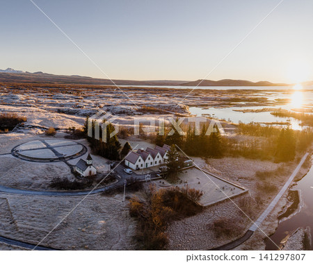 Aerial view of a church and historic buildings in Thingvellir National Park, Iceland, at sunrise with frosty winter terrain. Aerial view of a church and historic buildings in Thingvellir National Park, Iceland, at sunrise with frosty winter terrain. 141297807