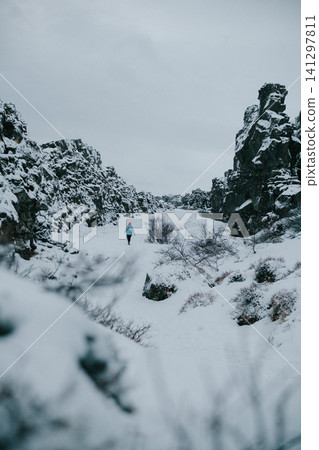Person hiking through a snowy gorge in Thingvellir National Park, Iceland. Person hiking through a snowy gorge in Thingvellir National Park, Iceland. 141297811