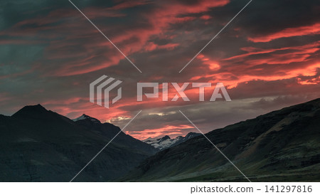 Fiery red and pink clouds during a stunning sunset over Hornafjordur, south Iceland. Fiery red and pink clouds during a stunning sunset over Hornafjordur, south Iceland. 141297816