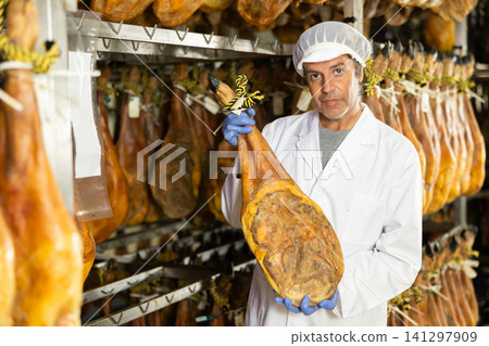 man checks the quality of ham in a factory man checks the quality of ham in a factory 141297909