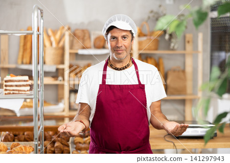 Middle-aged male seller stands in bake house, ready to greet customers 141297943