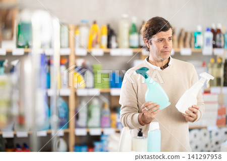 man chooses a spray to clean surfaces man chooses a spray to clean surfaces 141297958