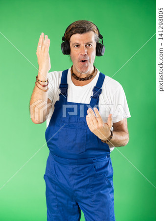 Man plumber with headphones, listening to music, having fun and dancing, enjoying dynamic music track. Man plumber with headphones, listening to music, having fun and dancing, enjoying dynamic music track. 141298005