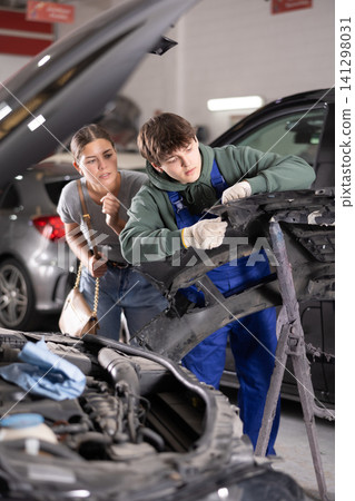 Mechanic consulting woman on car bumper repair Mechanic consulting woman on car bumper repair 141298031