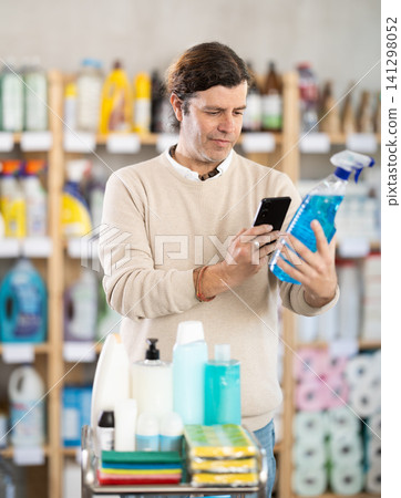 Middle-aged man scanning spray barcode in store Middle-aged man scanning spray barcode in store 141298052