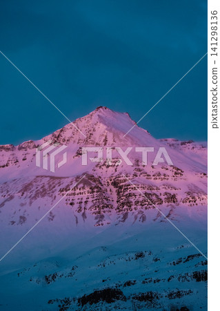 Pink alpenglow illuminates a snow-covered mountain peak in Hornafjordur, south Iceland. Pink alpenglow illuminates a snow-covered mountain peak in Hornafjordur, south Iceland. 141298136