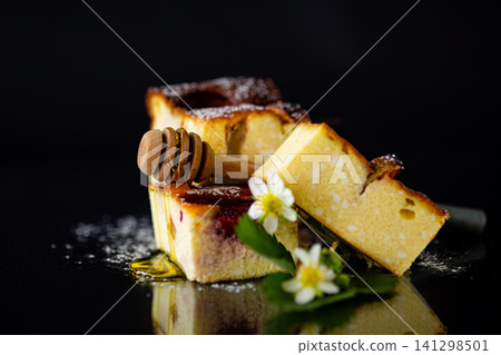 Golden baked cheesecake squares with strawberry topping on dark backdrop Golden baked cheesecake squares with strawberry topping on dark backdrop 141298501