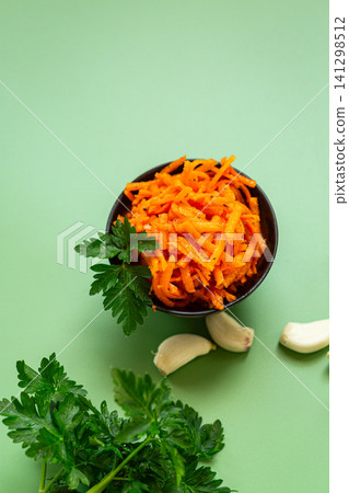 Healthy carrot appetizer in black bowl on green backdrop Healthy carrot appetizer in black bowl on green backdrop 141298512