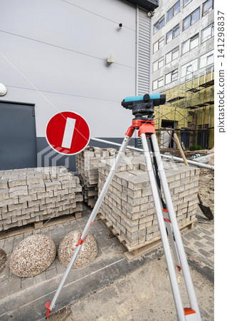 Surveying equipment is in front of stacked bricks and a no entry sign. Construction materials are lined up, ready to be utilized in the area Surveying equipment is in front of stacked bricks and a no entry sign. Construction materials are lined up, ready to be utilized in the area 141298837