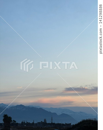 Soft sunset light over the Caucasus Mountains near Batumi, Georgia with pink clouds, layered hills, and silhouettes of trees 141298886
