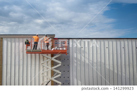 Construction Workers Installing Metal Wall Panels Construction Workers Installing Metal Wall Panels 141299923