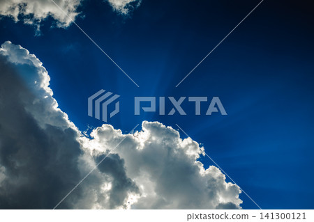 Dramatic blue sky with sun rays shining through fluffy white clouds Dramatic blue sky with sun rays shining through fluffy white clouds 141300121