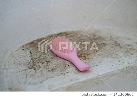 Pink hairbrush rests on dusty, cracked white surface Pink hairbrush rests on dusty, cracked white surface 141300665