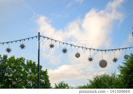 String lights hang above green trees under a blue sky 141300669