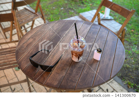 Cozy outdoor table holds sunglasses and iced drink Cozy outdoor table holds sunglasses and iced drink 141300670