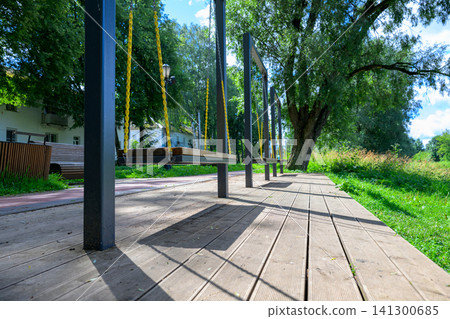 Wooden path lined with dark poles under bright sky 141300685