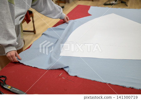 Person adjusts blue fabric on red surface Person adjusts blue fabric on red surface 141300719