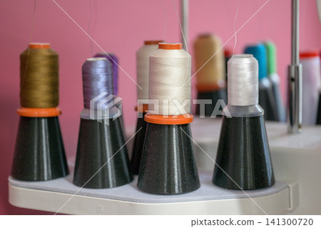 Colorful spools of thread sit neatly on a rack 141300720