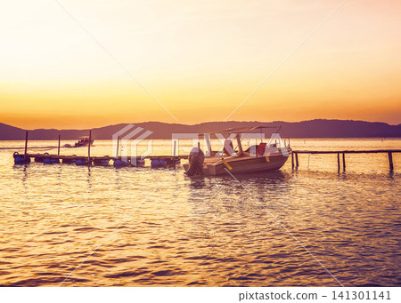 Speedboat moored to wooden pier at sunset. Pleasure boat Speedboat moored to wooden pier at sunset. Pleasure boat 141301141